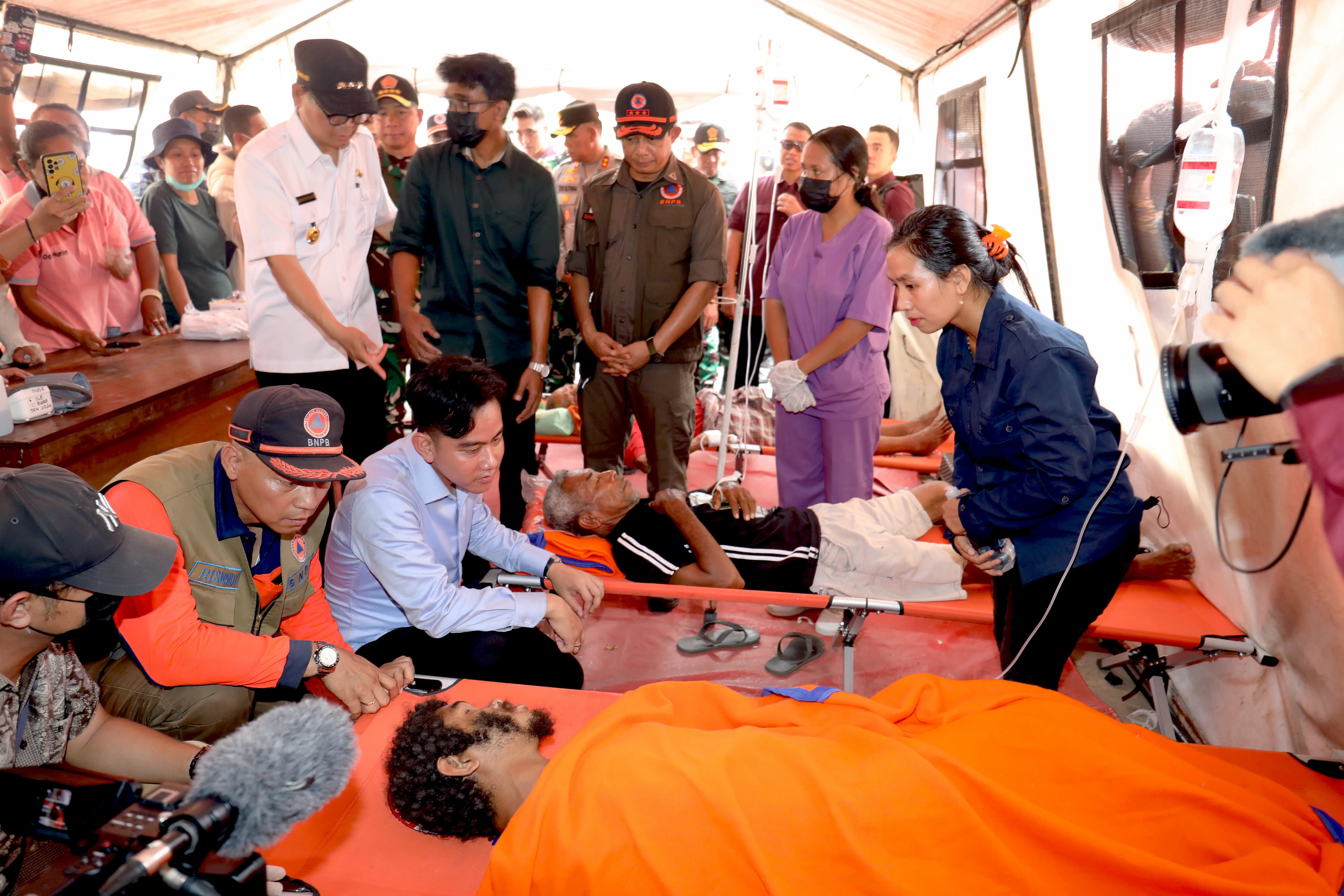 Wakil Presiden Republik Indonesia Gibran Rakabuming didampingi Kepala BNPB Letjen TNI Dr. Suharyanto, S.Sos., M. saat mengunjungi warga yang sedang di rawat di tenda kesehatan yang ada di pos lapangan  Desa Konga,  Kecamatan Titehena, Kabupaten Flores Timur, Nusa Tenggara Timur, pada Kamis (14/11).